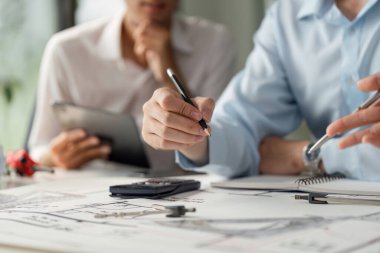 Mimarlar birlikte konut tasarımları üzerine beyin fırtınası yapar, mimari planlar tartışılırken minyatür bir ev modeliyle yaratıcı bir şekilde meşgul olurlar..