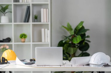 İnşaatta üretkenliği vurgulayan, canlı bir ortam yaratmak için gerekli araçları, dijital cihazları ve bitki dekorunu gösteren iyi düzenlenmiş bir çalışma alanı.