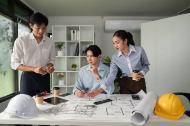 Mimari tasarım ve proje planları üzerinde işbirliği yapan üç profesyonel, modern bir çalışma alanında takım çalışması ve yenilikleri teşvik etmektedir..