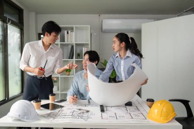 İşbirlikçi bir ortamda, ekip üyeleri proje oluşturma stratejilerini tartışıyor, mimari planlamada iletişim ve koordinasyonu vurguluyorlar.