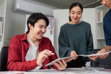 Üç birey, dijital tasarımlar hakkındaki düşüncelerini paylaşmak için yaratıcı bir çalışma alanında bir araya gelirler, projelerini geliştirmek için geri bildirim ve yeni fikirler sunarlar..