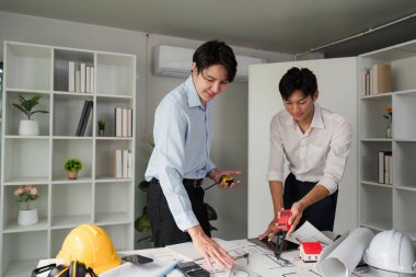 Meslektaşlar, inşaat projeleri için tasarım stratejisini optimize etmek için doğru ölçümlere odaklanarak, bina planlarının detaylandırılmasında işbirliği yaparlar..