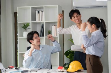 İşbirlikçi bir ortamda, üç genç profesyonel proje başarısı için heyecanı paylaşıyor. Takım çalışmaları iş yerinde coşku ve yaratıcılığı yansıtıyor..