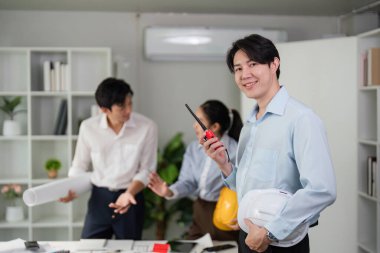 Ekip üyeleri tartışmalarla uğraşırken, inşaat projelerinin yönetiminde modern işbirliğini vurgulayarak yüksek teknolojili araçlar kullanıyorlar..