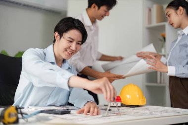 İş arkadaşları inşaat planları üzerinde aktif olarak işbirliği yapıyor, proje verimliliğini artırmak ve destekleyici bir çalışma ortamını desteklemek için fikir alışverişinde bulunuyorlar.