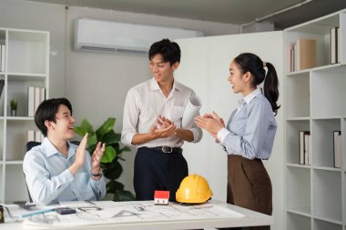 Ekip üyeleri kapsamlı bir tartışmanın ardından sevinçten havalara uçuyor ve proje planları üzerinde fikir birliğine vararak bir başarı hissi yaratıyorlar..