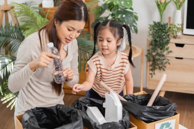 Bir ev etkinliği sırasında, anne ve çocuk geri dönüşümlü öğeleri birlikte sınıflandırarak, genç yaştan itibaren çevre bilincinin temelini oluştururlar..