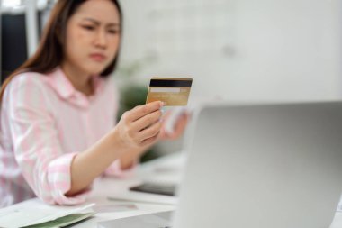 Ev ofisinde, bir kadın kredi kartı ekstrelerini dikkatle gözden geçirir. Verimli bir uzaktan kumandalı işçi olarak mali durumunu idare etmenin baskısını hisseder..