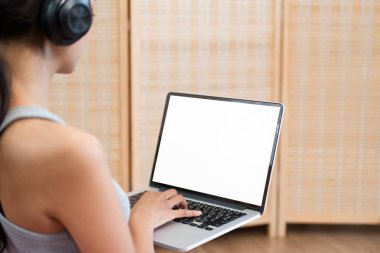 Rahatça oturarak, bir kadın laptopuyla meşgul oluyor, kulaklıklarının tadını çıkarırken derin odaklanmış ve bilgileri emiyor, üretken bir atmosfer yaratıyor..