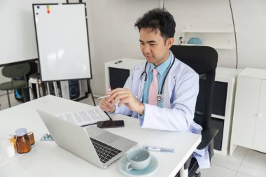 Hasta bakımına odaklanan doktor, tıbbi evrakları inceler ve hastalar için en iyi tavsiyeleri sağlamak için teknolojiyi kullanır..