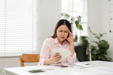 Genç bir kadın ofis masasında oturmuş mali işlerle uğraşıyor. Uzak işlerin ortasında harcamalarını ve faturalarını yönetmeye çalışırken kaygılarını dile getiriyor..