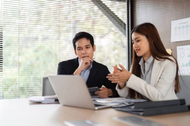 Bir kadın bir noktayı açıklarken, bir erkek dikkatle dinler, iş stratejileri içinde etkili iletişim ve işbirliğini teşvik eder..