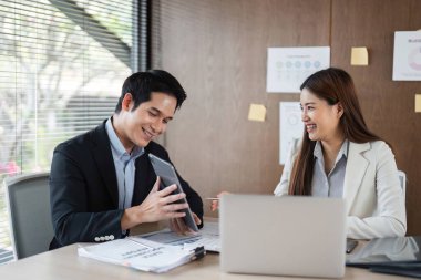 Erkek bir profesyonel meslektaşı ile keyifle etkileşime girer, bir tablette sergilenen bulguları tartışır, modern iş iletişimini ve takım çalışmasını sembolize eder..