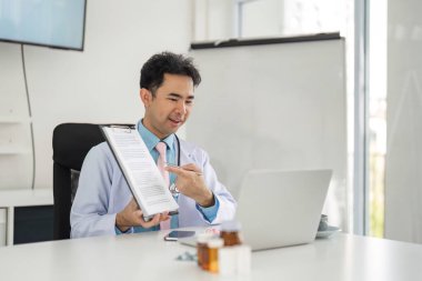 Doktor, bir tele sağlık ziyareti sırasında tıbbi dokümanları göstererek, hasta anlayışını ve katılımını destekleyerek profesyonelliğini gösteriyor..