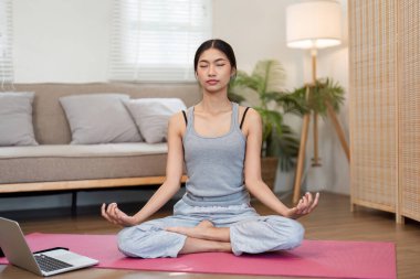 Huzurlu bir sahnede bir kadın meditasyon yapıyor, zihinsel berraklığına ve farkındalığına odaklanıyor ve rahat bir atmosferdeki genel sağlığını arttırıyor..