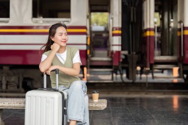 Genç bir kadın bir tren istasyonunda sakince oturup yolculuğunun başlamasını beklerken dinlenmek ve düşünmek için zaman ayırıyor. Atmosfer sükunet ve beklenti yayar..