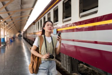 Hareketli bir tren istasyonunda, bir kadın akıllı telefonuyla meşgul olur, anılarını yakalar ve bir sonraki hedefini planlar..