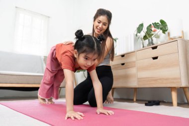 Sıcak bir yoga alanında, bir çocuk öğretmeninin teşvik edici rehberliğiyle, fiziksel aktivite ve büyüme için sevgi dolu bir ortam oluşturmaya çalışır..