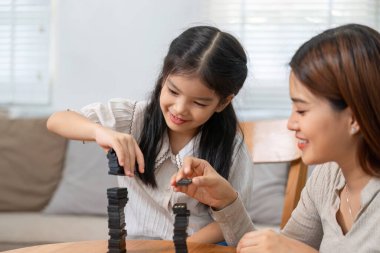 Bir anne ve kızı eğlenceli bir oyun oynuyorlar, domino oynuyorlar ve birlikte iyi vakit geçiriyorlar, yaratıcılığı ve bağlantıyı teşvik ediyorlar..