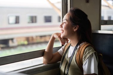 Huzurlu bir gezgin pencereden dışarı bakar, yolculuğunu yansıtır ve bir sonraki durakta onu bekleyen maceraları hayal eder..