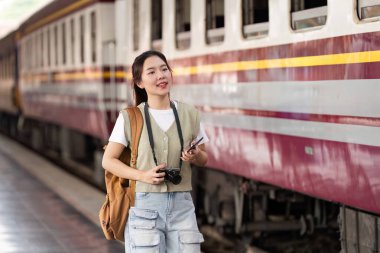 Genç bir kadın tren istasyonunda duruyor. Seyahat macerasına atılma heyecanıyla dolu. Akıllı telefonunu kontrol ederken kamerasıyla anları yakalıyor..
