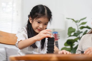 Genç bir kız, kayalardan oluşan uzun bir yapı yaratmaya odaklanır. Annesinin rehberliğinde azim ve ilgi gösterir..