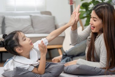 Kahkahaların ortasında, bir anne ve kız neşeli beşliklerle başarılı bir oyun kutluyor, neşeli ilişkilerini sergiliyorlar..