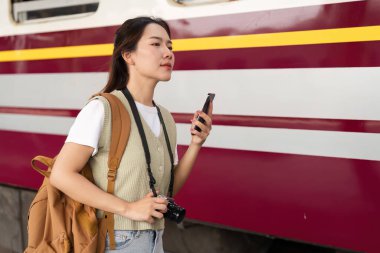 Hareketli bir tren istasyonunda, akıllı telefonuyla meşgul olan genç bir kadın yolculuk maceralarını heyecanla beklerken, kamera yolculuk için hazır..