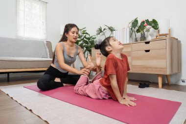 Besleyici bir yoga eğitmeni, kobra pozu veren bir çocuğa destek olur, esnekliklerini arttırır ve sakin bir ev ortamında dikkatli bir hareketi teşvik eder..
