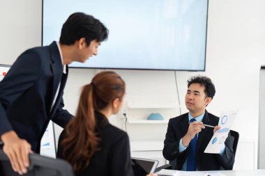 Üç meslektaşı proje verilerini tartışıyor ve modern ofis ortamında görüşleri paylaşıyor, takım çalışması ve iletişim sergiliyorlar.