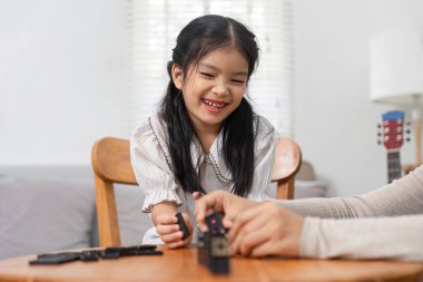 Bir kız oyun oynarken neşeyle ışıldar, aile oyun gecelerinde meydana gelen mutluluk ve bağları gösterir..