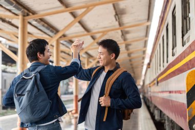 İki arkadaş, tren istasyonunda keyifli bir beşlik çakar. Yolculuk maceralarına hazırlanırlar..