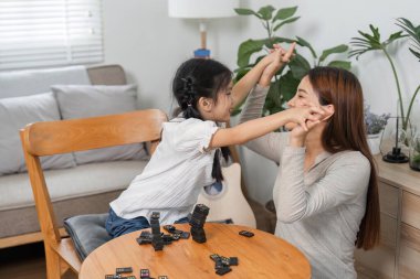 Anne ve kızı, aile yaşamında sevgi ve kahkahayı vurgulayarak domino oyununun tadını çıkarırken, neşeli bir etkileşim gerçekleşir..