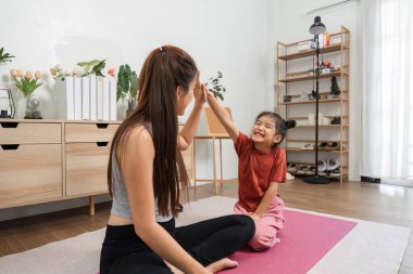 Bir anne ve kızının etkileşimli bir egzersiz yaptığı spor seansı. Spor ve kahkahalarla bağlanma üzerine..