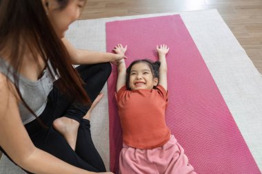 Bir anne kızıyla neşeli bir esneme seansını paylaşır. İçi kahkaha ve cesaretle dolu. Formda olmanın sevincini vurgular..