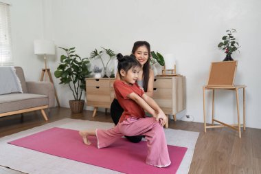 Bir anne yoga pozlarında kızına rehberlik ederken eğlenceli bir etkileşim başlar. Oturma odalarında egzersiz ve bağ kurmak için eğlenceli bir alan yaratır..