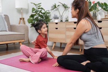 Huzurlu bir ev ortamında, bir anne kızını bir meditasyon uygulamasına yönlendirir, paylaşılan deneyim yoluyla farkındalığı ve iç huzuru teşvik eder..