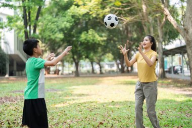 Çocuklar topu ileri geri atarak, her başarılı yakalamayı neşeyle ve kahkahalarla kutlayarak futbol becerilerini geliştiriyorlar..