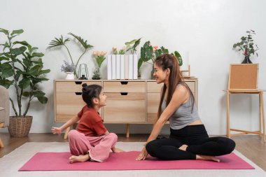 Bir anne ve kızı, yoga minderleri üzerinde esneme egzersizleri yaparken, sağlık ve ilişki geliştirme egzersizleri yaparken aynı kahkaha ve bağlantıyı paylaşıyor..