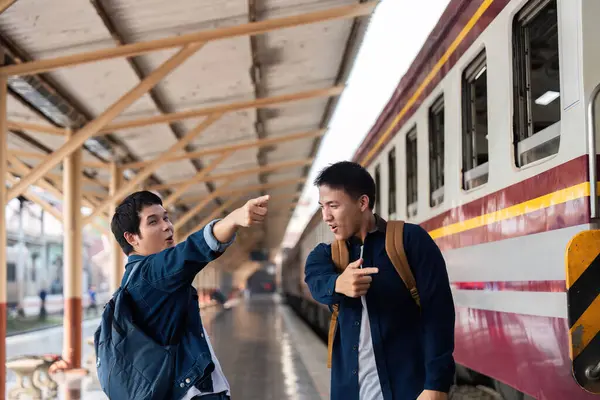 İki arkadaş hareketli bir şekilde seyahat planlarını tartışıyor ve yola çıkmadan önce tren istasyonunda coşkularını sergiliyorlar..