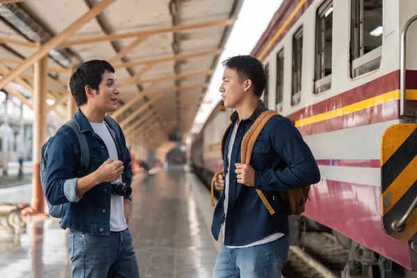 İki arkadaş hareketli bir şekilde tren istasyonunda yapacakları geziyi tartışıyor, keşif için bağlarını ve coşkularını sergiliyorlar..