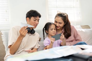 Yaratıcı bir aktiviteye katılan bir aile, kızı akıllı telefondan öğrenirken bir arada oturur ve ebeveynlikteki teknolojinin değerini güçlendirir..