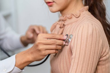 Bir doktor rutin bir kontrol sırasında steteskop kullanan bir hastayı muayene eder, proaktif sağlık hizmetlerini teşvik eder ve potansiyel sorunların erken tespiti.