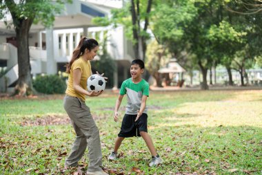 Çocuklar bir futbol oyununa dalmış, oyun yoluyla sosyal becerilerini geliştirirken, açık hava aktivitelerine olan heveslerini ve enerjilerini sergiliyorlar..