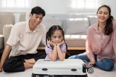 Bir kızın bir bavula neşeli bir şekilde oturması ve ebeveynlerinin sevinç ve heyecan dolu aile seyahatlerini resmetmesi gibi büyüleyici bir an yaşanıyor..