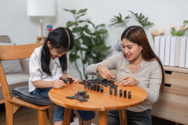 Bir anne ve kız domino oyunu sırasında strateji geliştirirken, aile ilişkilerinin oyuncu senaryolardaki önemini vurgulayan heyecan artar..