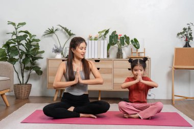 Huzurlu bir ev ortamında, bir anne ve kız yoga yaparlar, nefeslerini uyumlu hale getirirler ve ortak farkındalık ve oyuncu etkileşimler yoluyla daha derin bir bağ kurarlar..