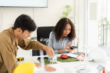 Bu resimde, iki meslektaş sürdürülebilir konut modellerini inceleyerek ve bunların modern yaşamda etkinliğini tartışarak dinamik bir sohbete girişiyor..