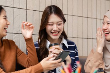 Üç arkadaş, rahat bir kafede kahkahalarla kahkahalarını paylaşıyor, kahve ve bağlantıyla rahat bir anın tadını çıkarırken, bağlarını derinleştiriyorlar..