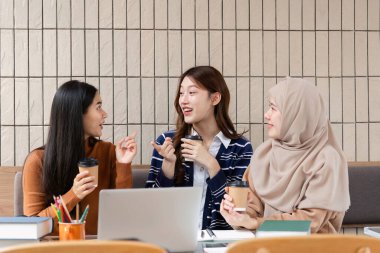 Üç arkadaş, kahvelerini yudumlarken hareketli bir sohbete girişiyor, modaya uygun bir kafede ortak bir atmosferin tadını çıkarıyorlar..